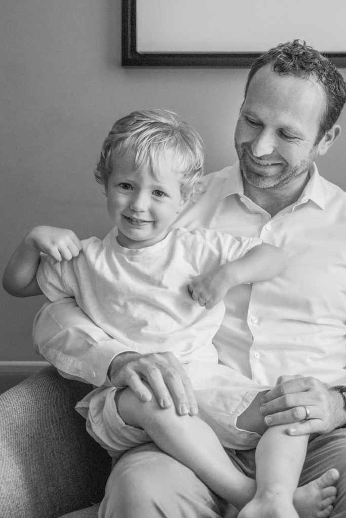 Black and white photo of a father carrying his young son on his lap
