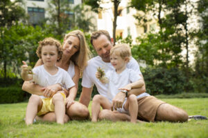 A couple and their young children (boys) sitting on a patch of grass