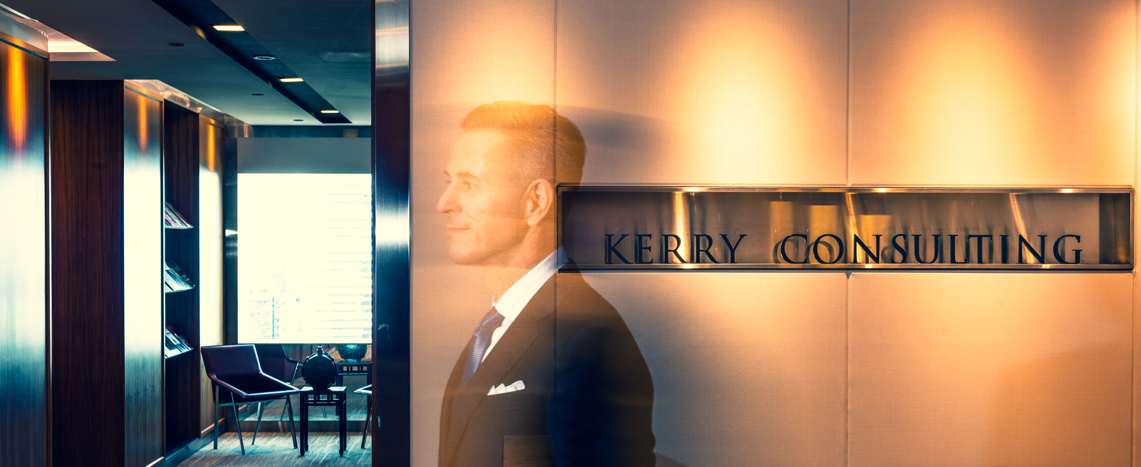 Long exposure shot of a man in a business suit and tie walking past company signage at reception area