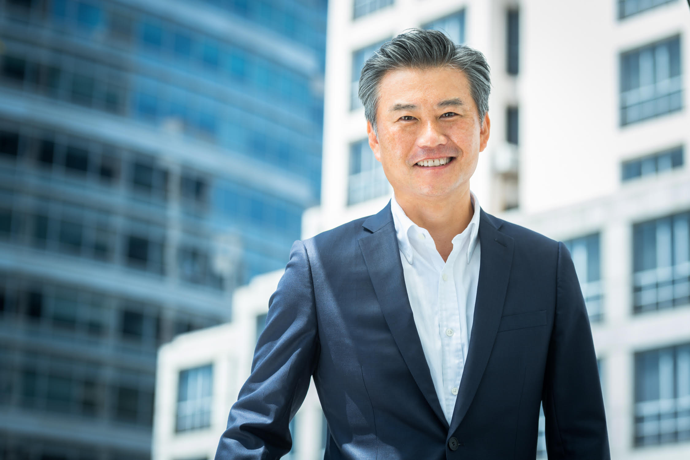 Man in a formal corporate suit poses for his headshot in front of office building during a professional headshot photoshoot in Singapore, White Room Studio. Credit: White Room Studio