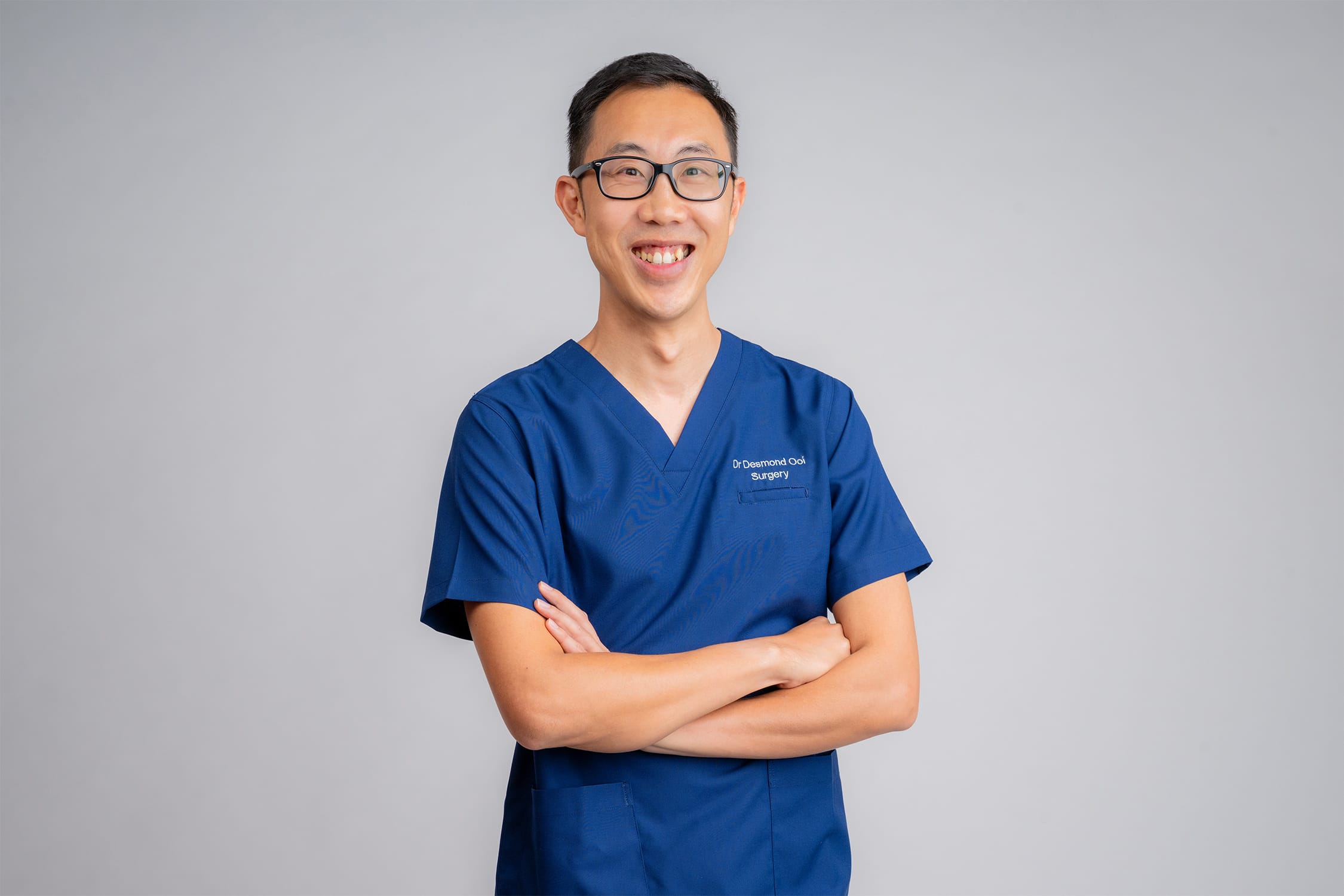 Surgeon wearing scrubs posing for headshot in a photography studio setting during a corporate photoshoot in Singapore, White Room Studio. Credit: White Room Studio Pte Ltd