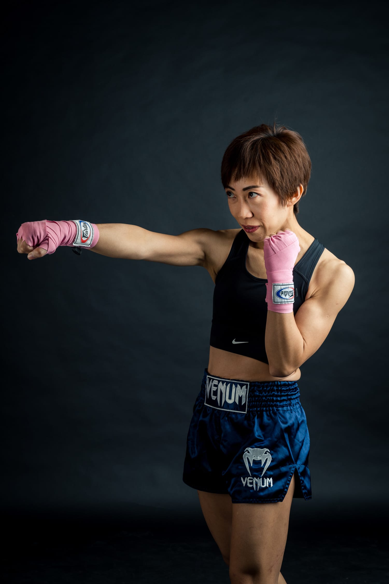Woman in muay thai boxing gloves and boxing shorts posing in a photography studio setting during a personal branding photoshoot in Singapore, White Room Studio. Credit: White Room Studio Pte Ltd