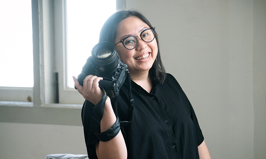Woman smiling holding a professional digital camera by White Room Studio during a portrait photoshoot in Singapore, White Room Studio. Credit: White Room Studio Pte Ltd