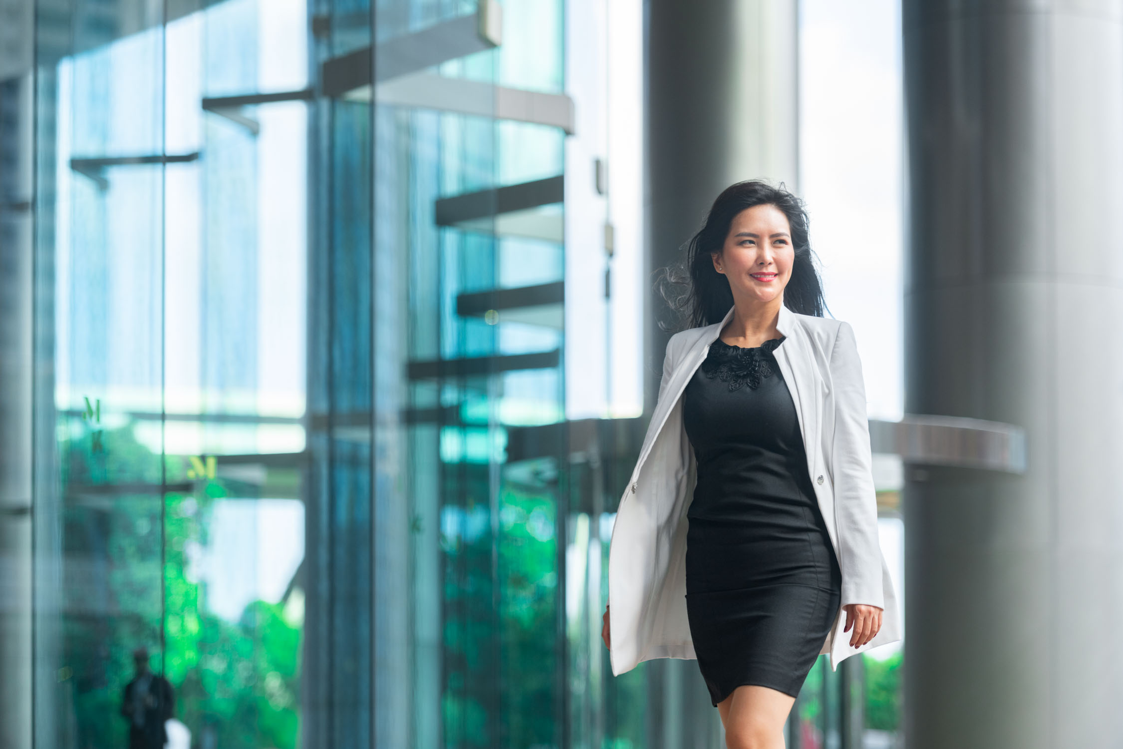 Asian woman in a formal business dress and blazer walking outdoors in Singapore
