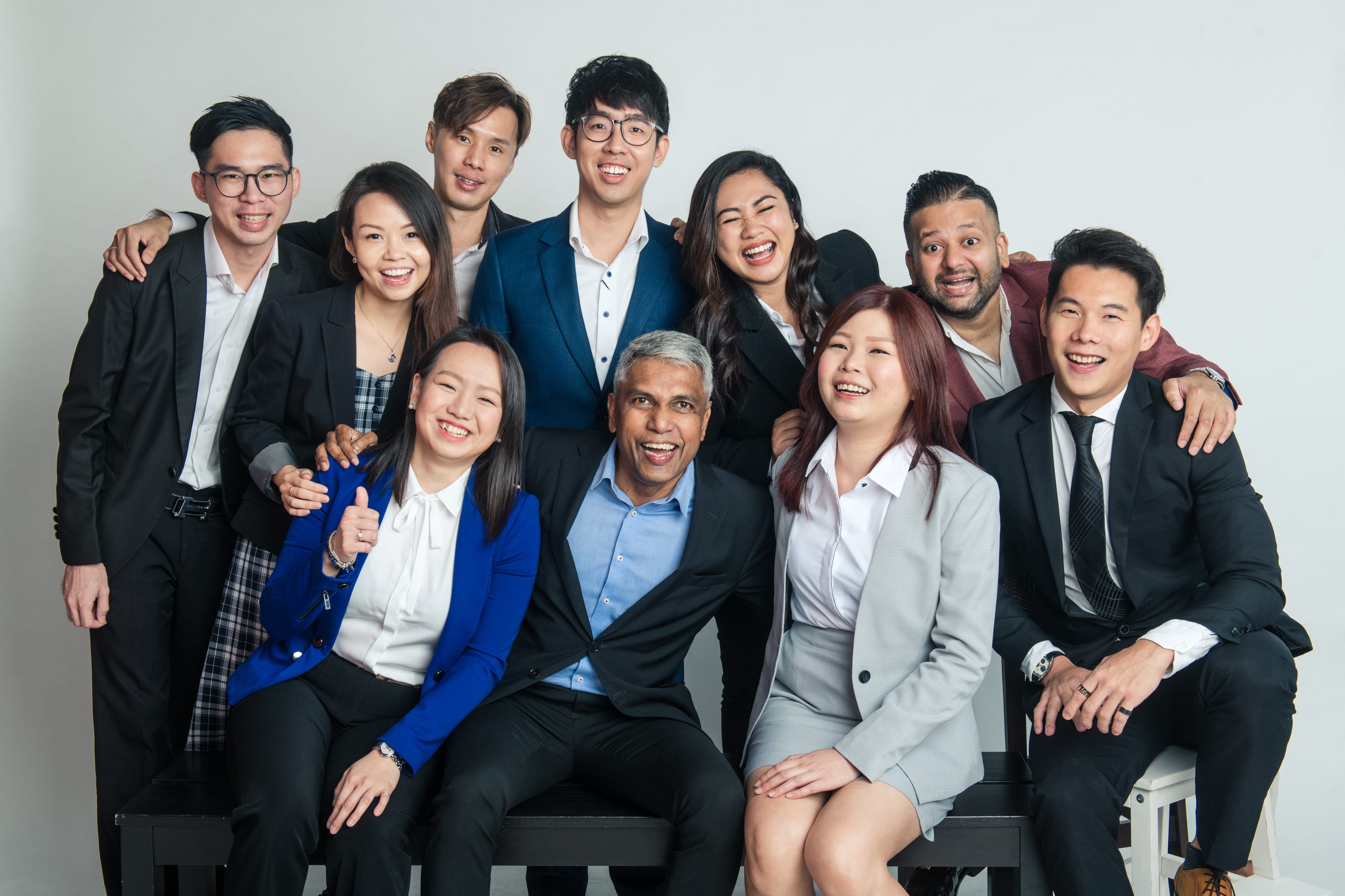 A group photo of business professionals smiling together with their arms around each other's shoulders during a corporate photoshoot in Singapore Credit: White Room Studio