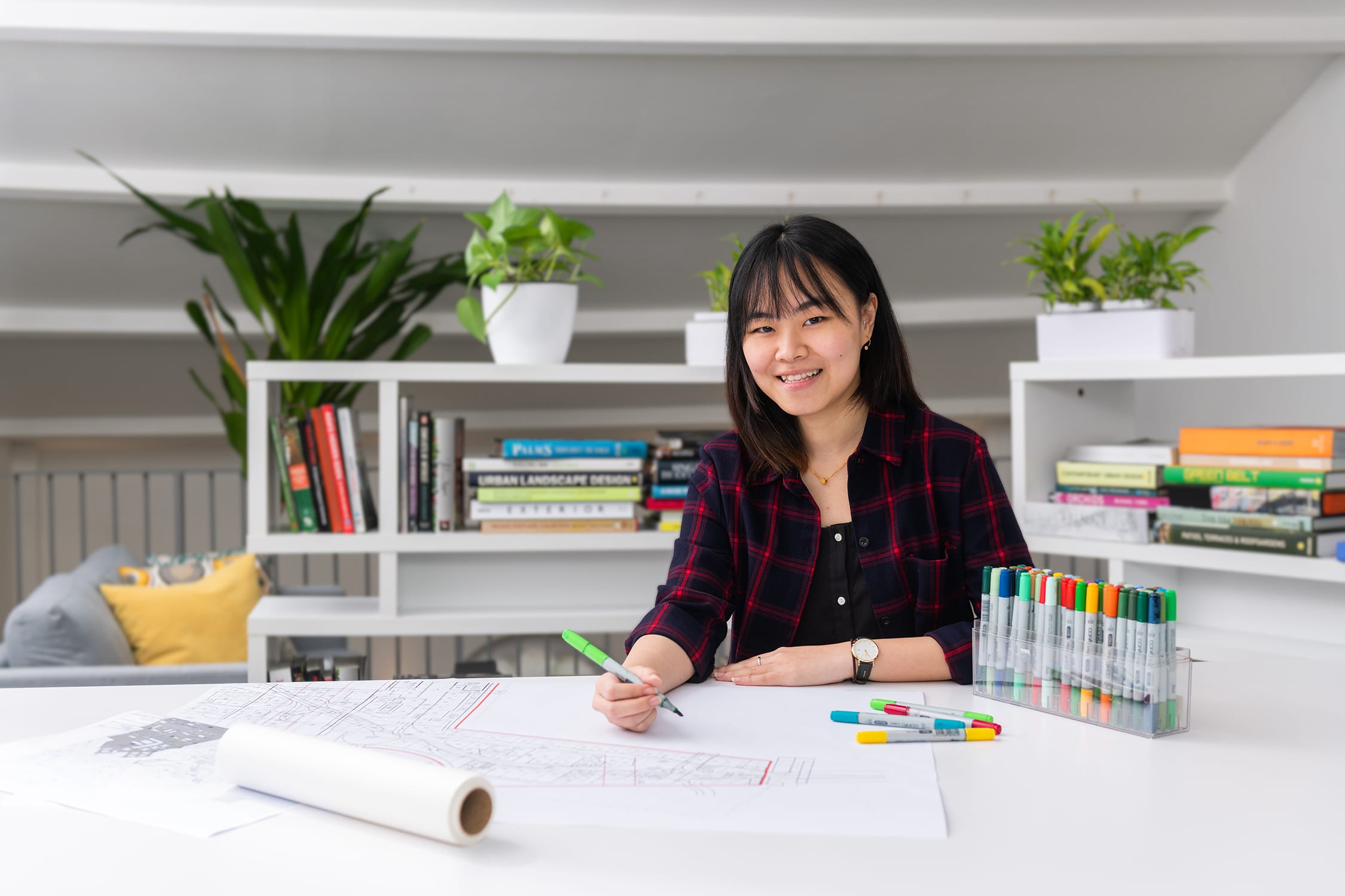 A woman working on a project in an office setting, smiling for her headshot during a corporate photoshoot in Singapore Credit: White Room Studio
