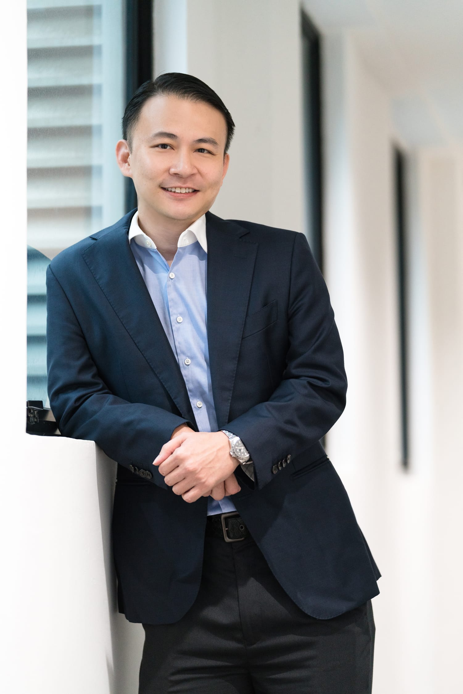 A man in a formal business suit poses for his headshot in an office setting during a corporate photoshoot in Singapore Credit: White Room Studio