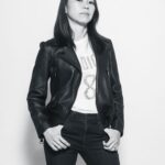 Black and white photo of a woman posing for her photo, Wearing a black leather jacket and black jeans during a professional indoor photo shoot in Singapore