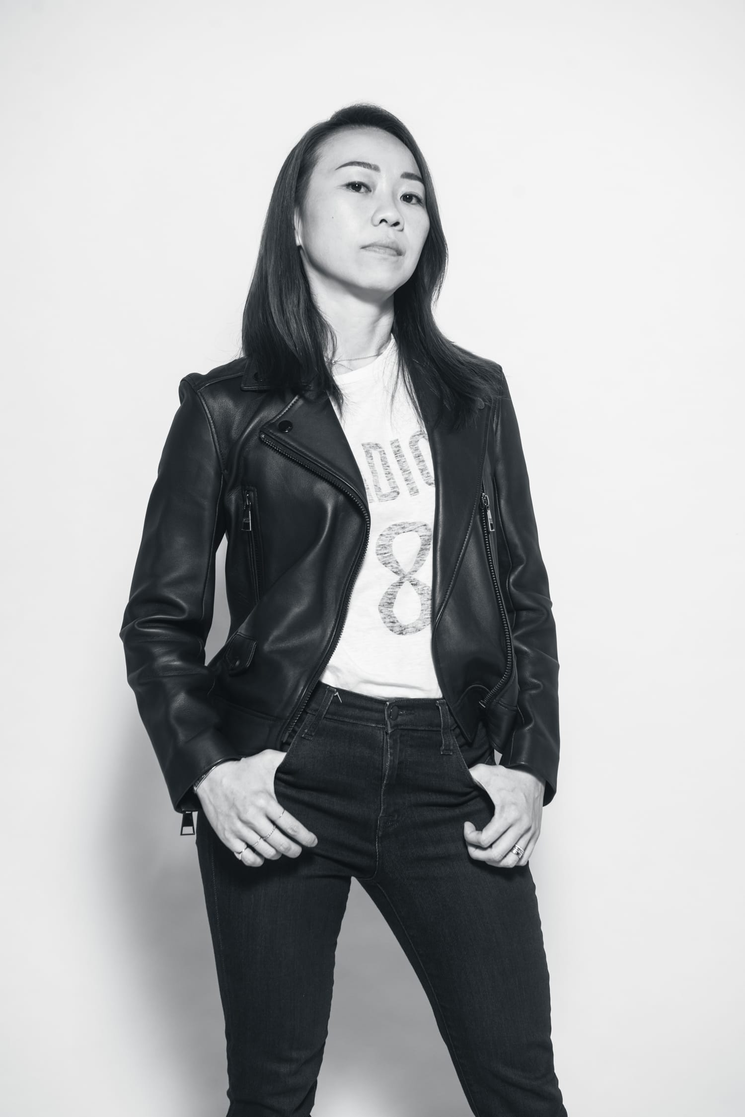 Black and white photo of a woman posing for her photo, Wearing a black leather jacket and black jeans during a professional branding photoshoot in Singapore Credit: White Room Studio