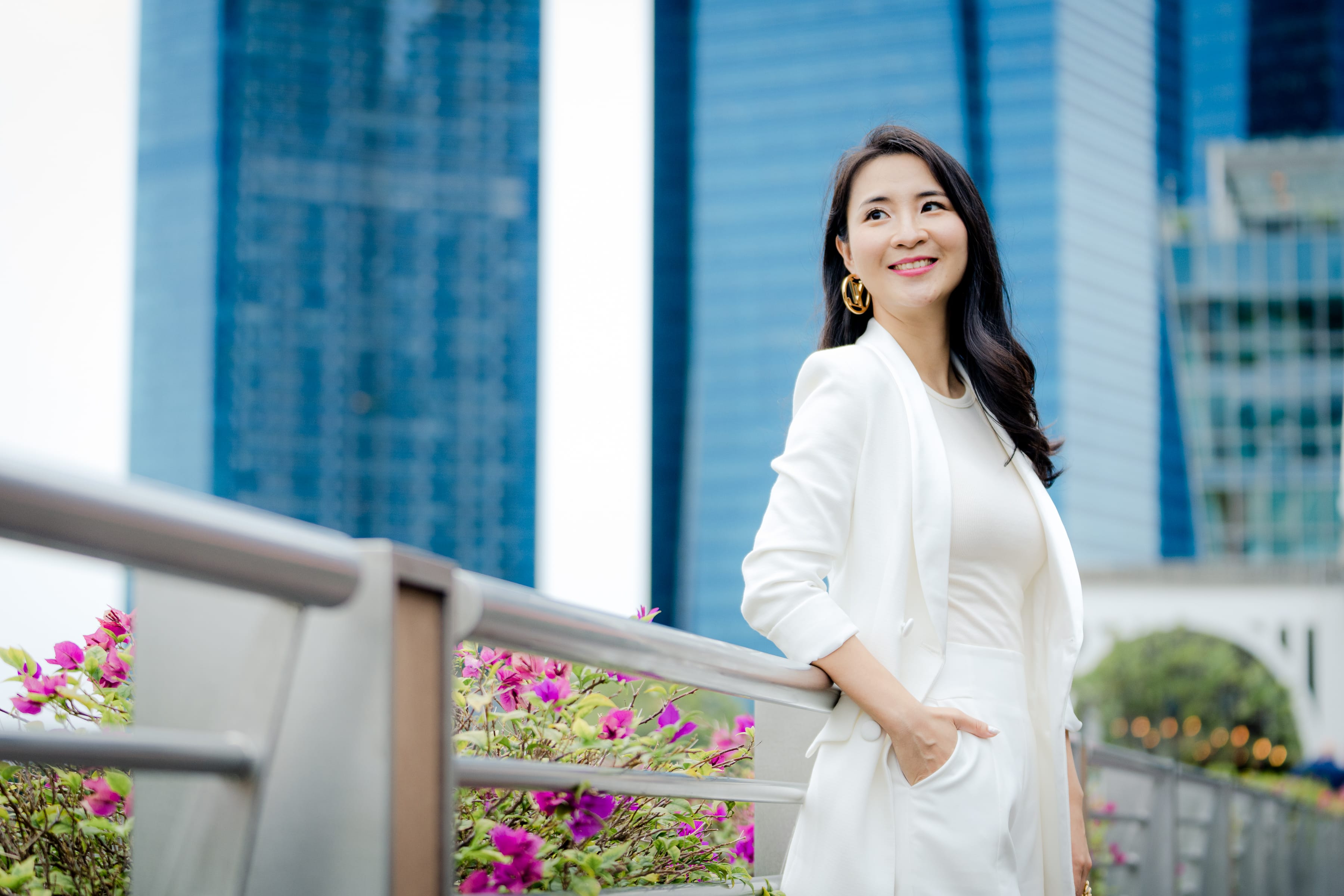 personal-branding-photoshoot-singapore-outdoors Woman smiling and standing professional headshot with skyscrapers and office buildings behind in Singapore White Room Studio Credit: White Room Studio Pte Ltd