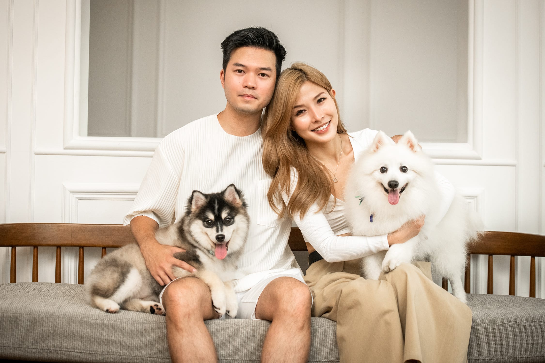 A couple hugs their pet dogs (husky and Japanese spitz)