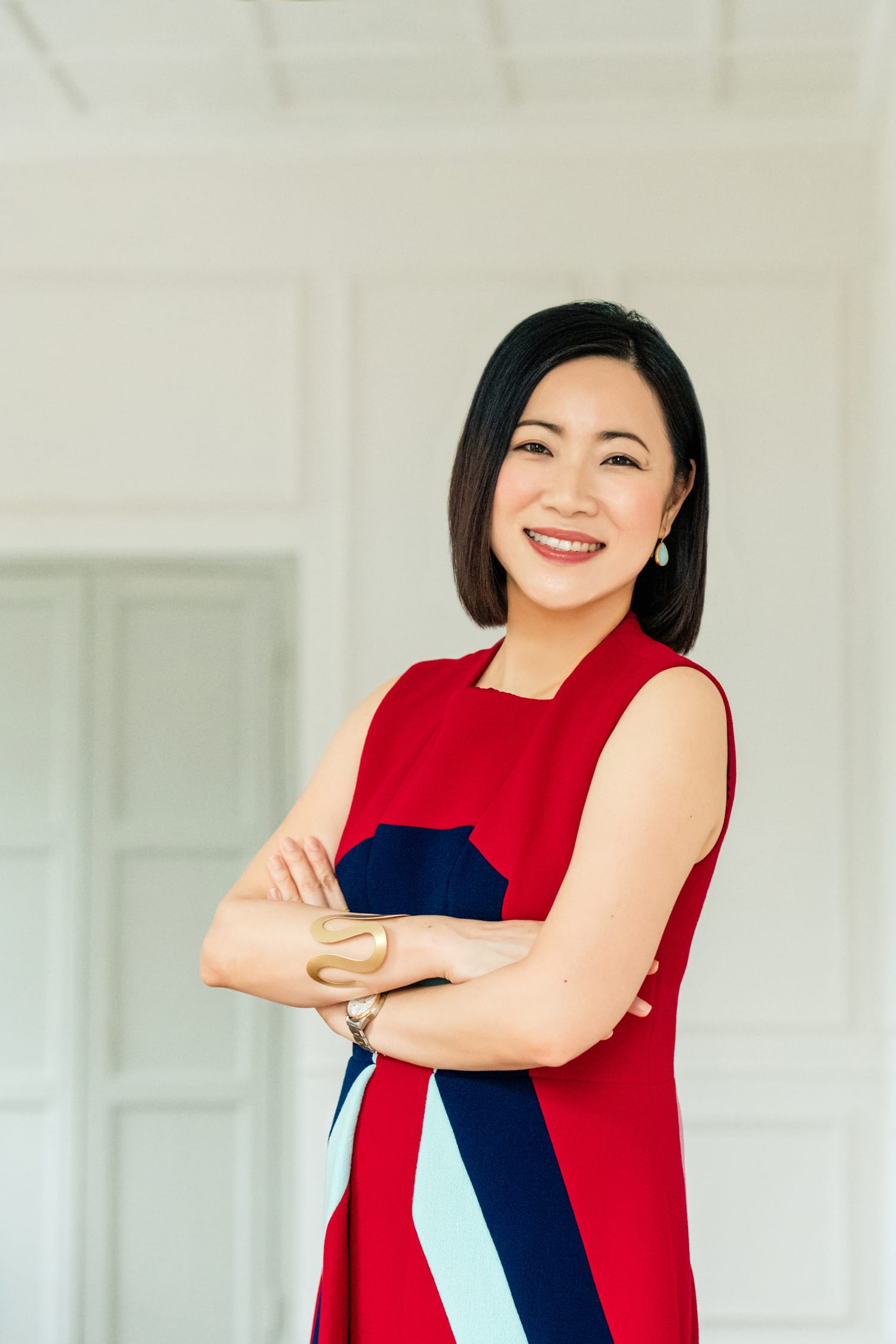 A woman in a red dress posing for her headshot with her arms folded across her chest during a corporate photoshoot in Singapore Credit: White Room Studio