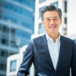 A man in a formal business suit posing for a headshot against office building during a corporate photoshoot in Singapore Credit: White Room Studio