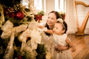 Mother and daughter looking at Christmas tree with harp in the background during Christmas family photoshoot in Singapore Credit: White Room Studio