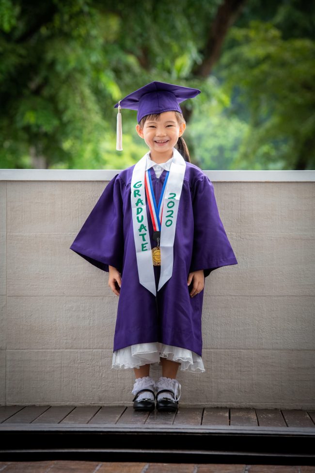 Girl in purple K2 kindergarten graduation gown and cap with nature scenery background during a K2 kindergarten graduation photoshoot in Singapore Credit: White Room Studio