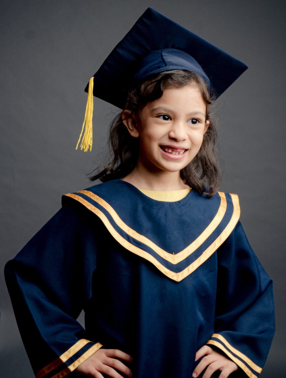 Girl in K2 kindergarten graduation gown and cap with black studio background during a K2 kindergarten graduation photoshoot in Singapore Credit: White Room Studio