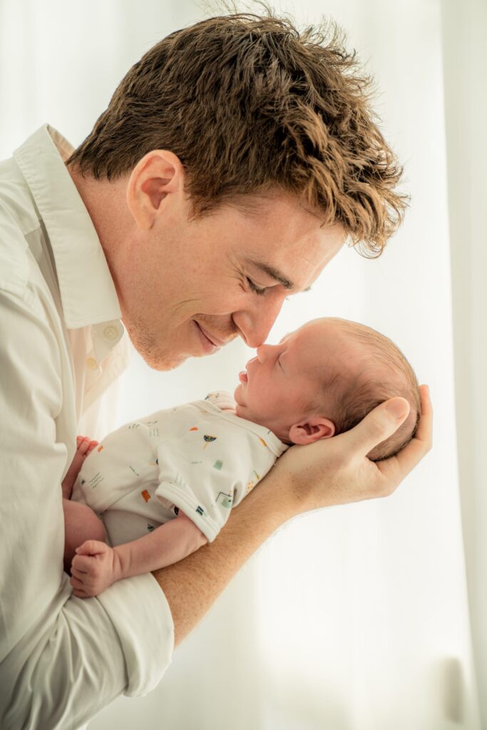Father carrying his newborn baby during a newborn photoshoot at White Room Studio Singapore