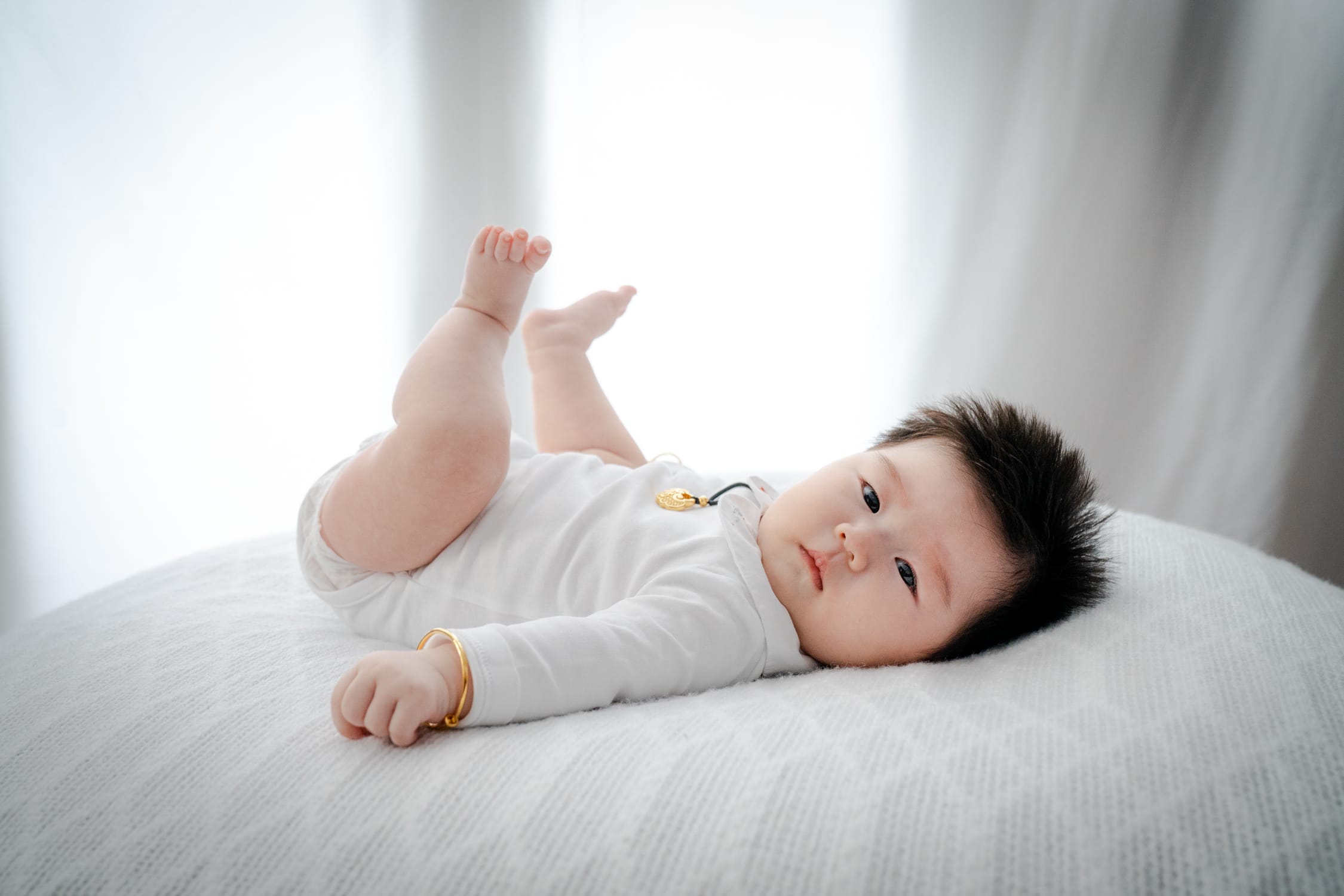 Newborn baby lying down with feet up in a photography studio setting during a natural light newborn photoshoot in Singapore, White Room Studio. Credit: White Room Studio Pte Ltd