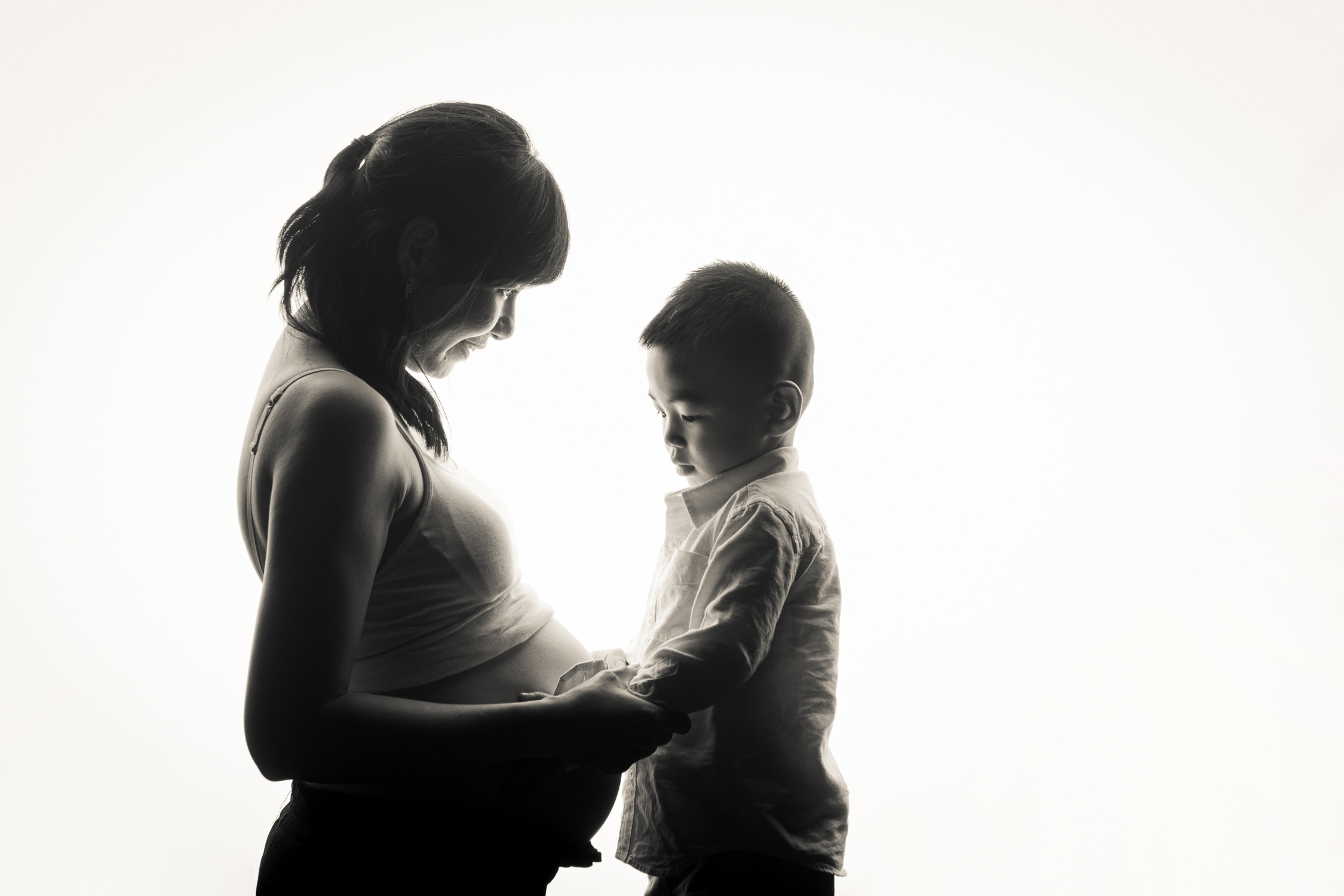Professional Maternity Photoshoot in Photography Studio, Singapore Pregnant mother, mother-to-be with baby bump smiling with son in a photography studio setting during a maternity photoshoot in Singapore, White Room Studio. Credit: White Room Studio Pte Ltd
