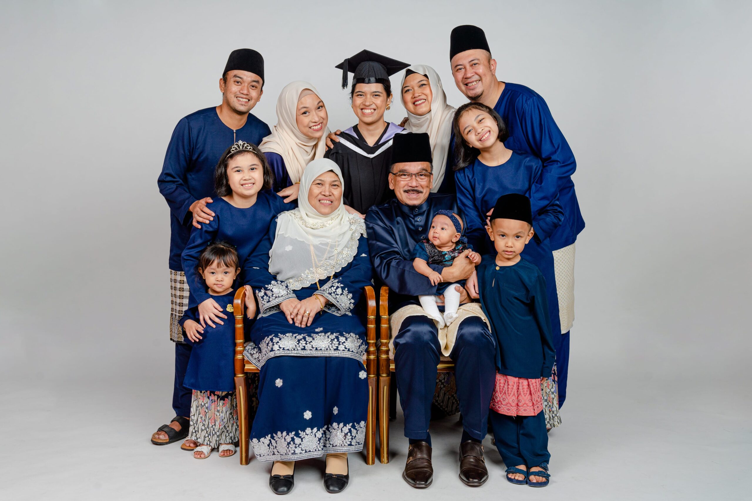 Family with parents and their children with kids ages ranging from toddler to teens wearing Hari Raya baju in a photography studio setting during a family Hari Raya photoshoot in Singapore, White Room Studio. Credit: White Room Studio Pte Ltd