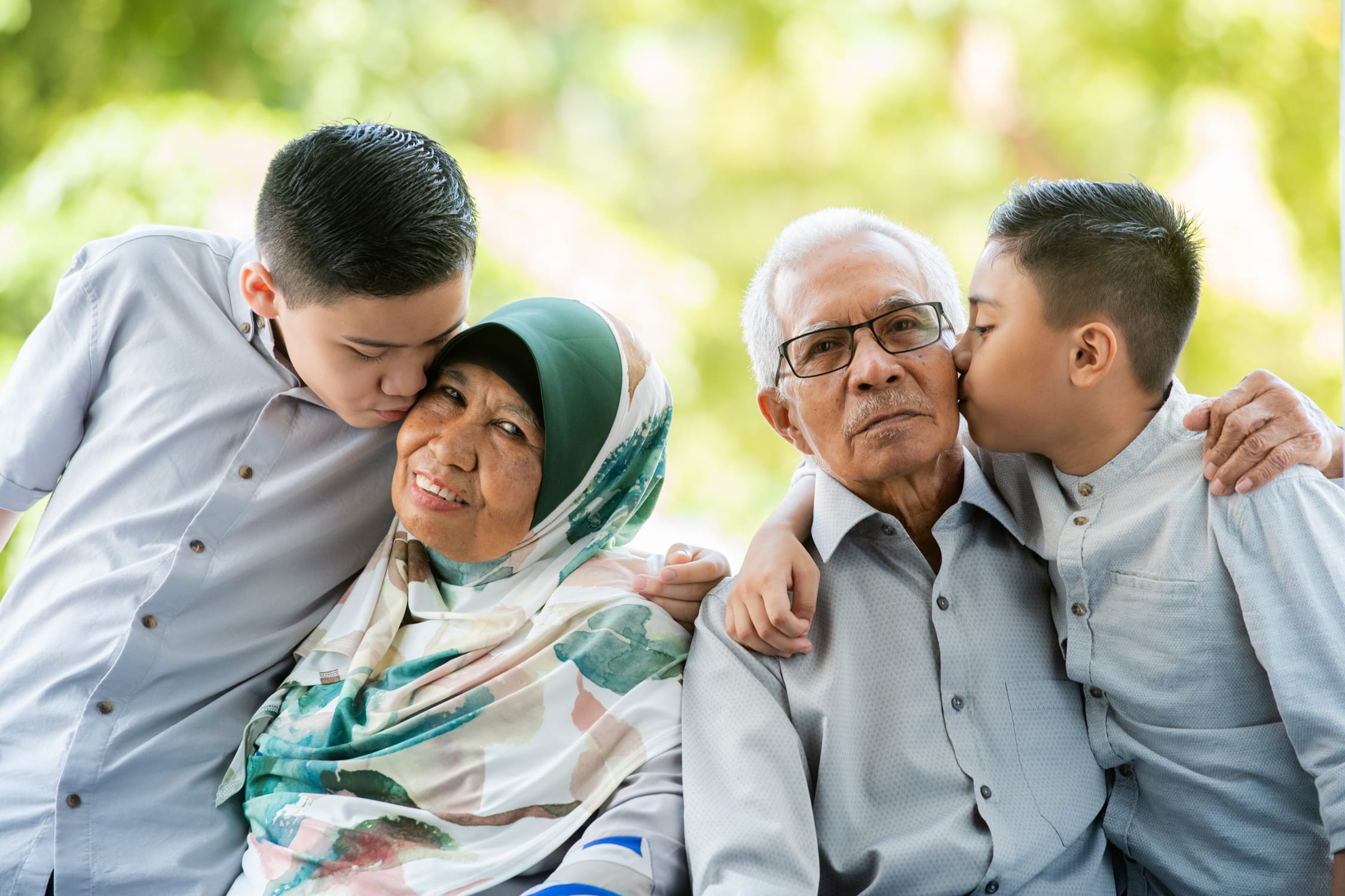 Professional Family & Multi Generation Photoshoot in Photography Studio, Singapore Two kids kissing grandparents on cheek in a photography studio setting during a Malay Muslim family Hari Raya photoshoot in Singapore, White Room Studio. Credit: White Room Studio Pte Ltd