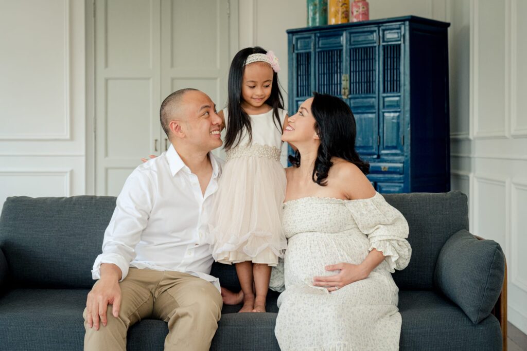 Professional Maternity Photoshoot in Photography Studio, Singapore Family with father and pregnant mother, mother-to-be with baby bump and kid in a photography studio setting during a maternity photoshoot in Singapore, White Room Studio. Credit: White Room Studio Pte Ltd
