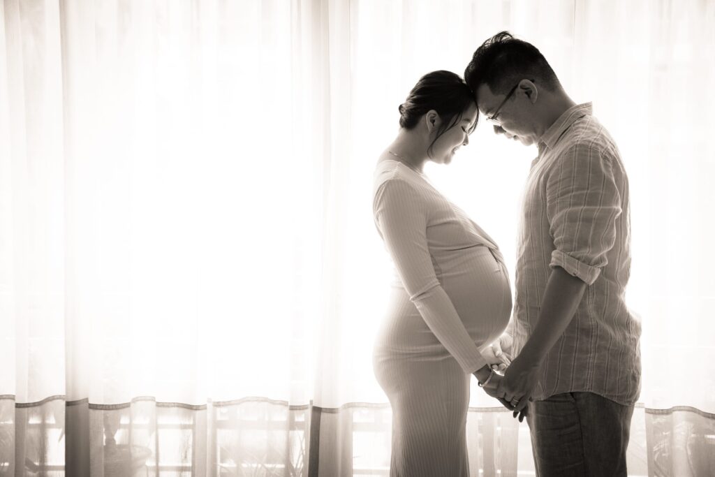 Professional Maternity Photoshoot in Photography Studio, Singapore Husband hugging pregnant wife, mother-to-be with baby bump in a photography studio setting during a maternity photoshoot in Singapore, White Room Studio. Credit: White Room Studio Pte Ltd
