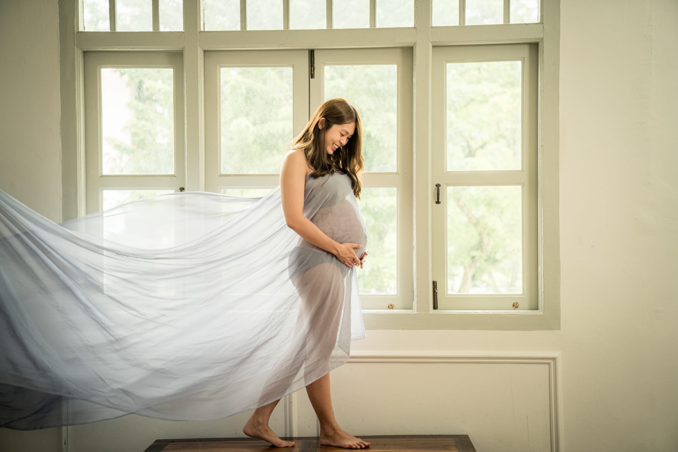 Pregnant mother, mother-to-be with baby bump in a photography studio setting during a maternity photoshoot in Singapore, White Room Studio. Credit: White Room Studio Pte Ltd