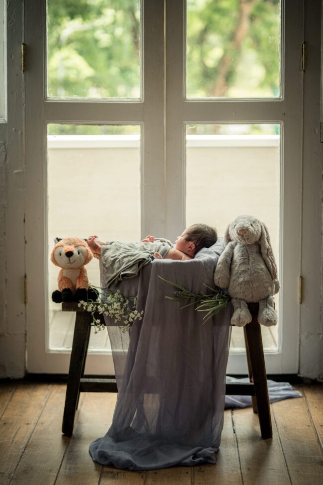 Newborn baby sleeping in a basket with blanket in a photography studio setting during a newborn photoshoot in Singapore, White Room Studio. Credit: White Room Studio Pte Ltd