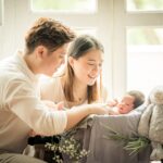 Family with parents and their newborn baby in a photography studio setting during a newborn photoshoot in Singapore, White Room Studio. Credit: White Room Studio Pte Ltd