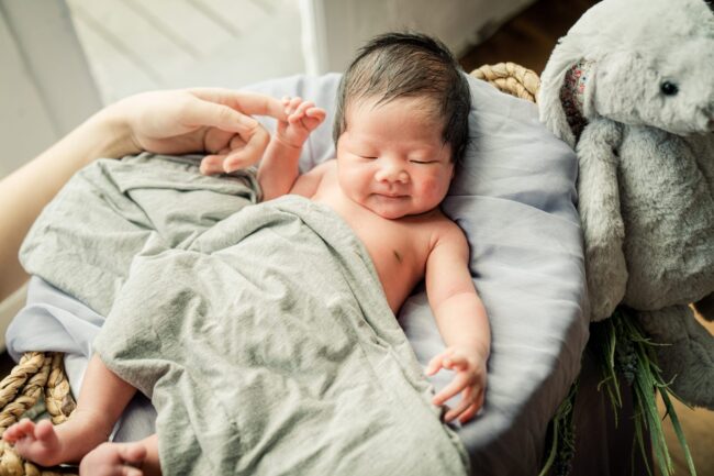 Family with parents and their newborn baby in a photography studio setting during a newborn photoshoot in Singapore, White Room Studio. Credit: White Room Studio Pte Ltd