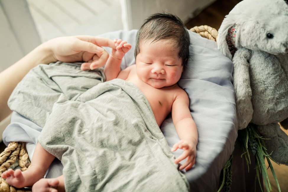 Family with parents and their newborn baby in a photography studio setting during a newborn photoshoot in Singapore, White Room Studio. Credit: White Room Studio Pte Ltd