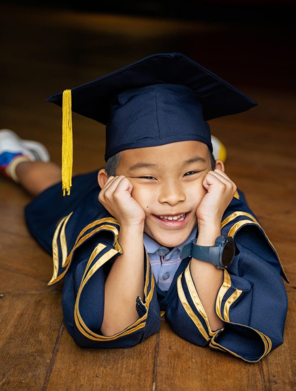 Boy in K2 kindergarten graduation gown and cap with black studio background during a K2 kindergarten graduation photoshoot in Singapore Credit: White Room Studio
