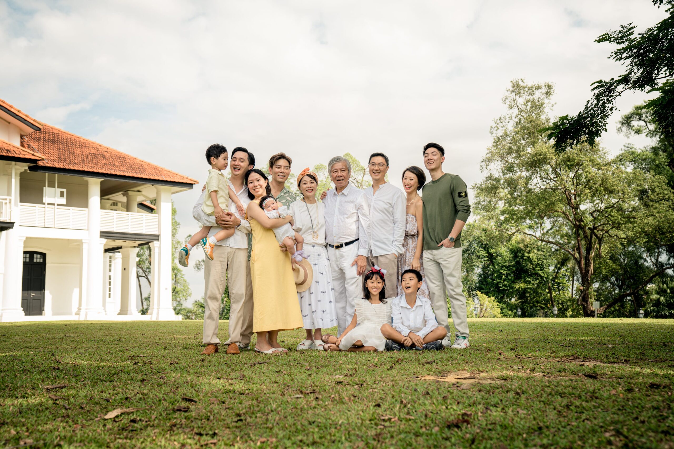Multi generation family with grandparents and parents hugging their children during a family outdoor photoshoot in Singapore, Botanic Gardens. Credit: White Room Studio Pte Ltd