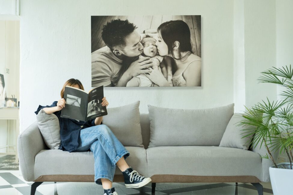 Fine-art canvas print of a family with parents and their newborn baby in a photography studio setting during a newborn photoshoot in Singapore, White Room Studio. Credit: White Room Studio Pte Ltd