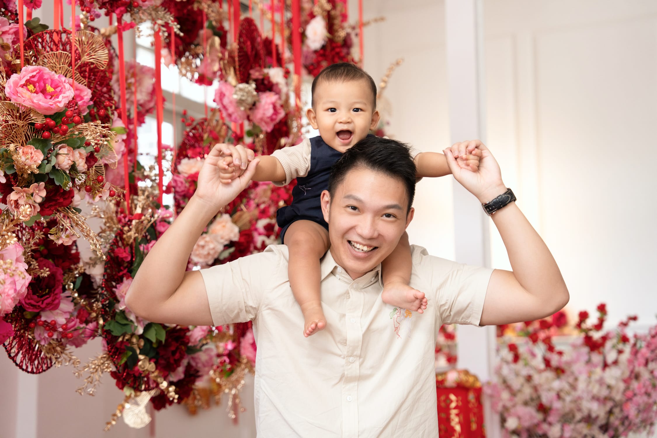 Family with dad carrying baby son on shoulders in a photography studio setting during a family Chinese New Year photoshoot in Singapore, White Room Studio. Credit: White Room Studio Pte Ltd