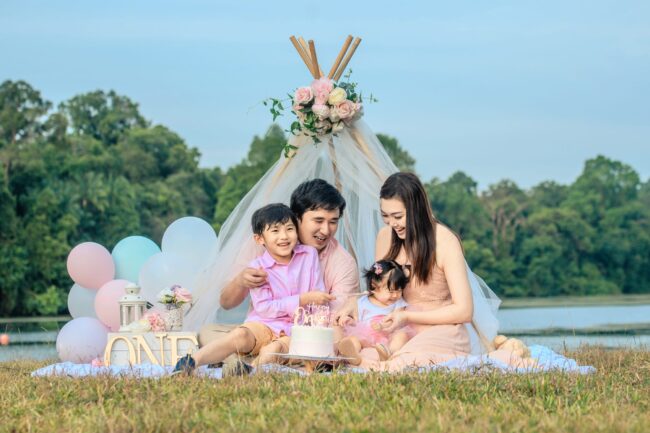 Family with parents and their children in a photography studio setting during an outdoor cake smash photoshoot in Singapore, Upper Peirce Reservoir Park. Credit: White Room Studio Pte Ltd