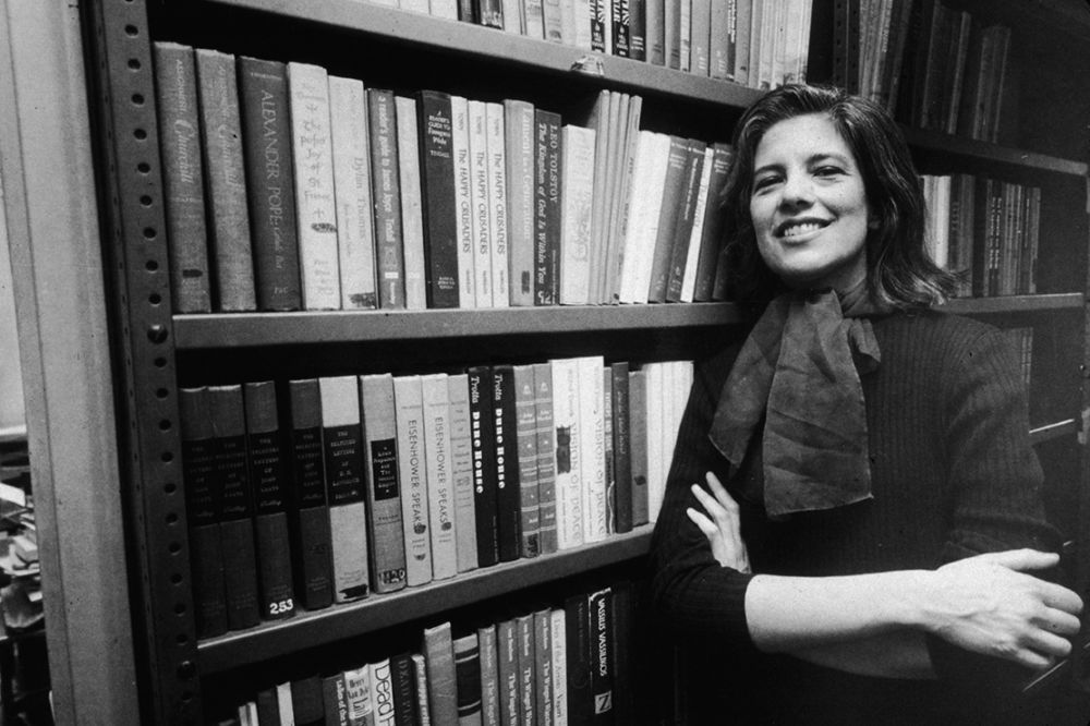 Portrait of American author and critic Susan Sontag (1933 - 2004) smiles broadly as she leans, arms crossed, against a bookshelf in the offices of her publisher, Farrar, Straus, and Giroux, New York, New York, January 23, 1978. (Photo by William E. Sauro/New York Times Co./Getty Images)