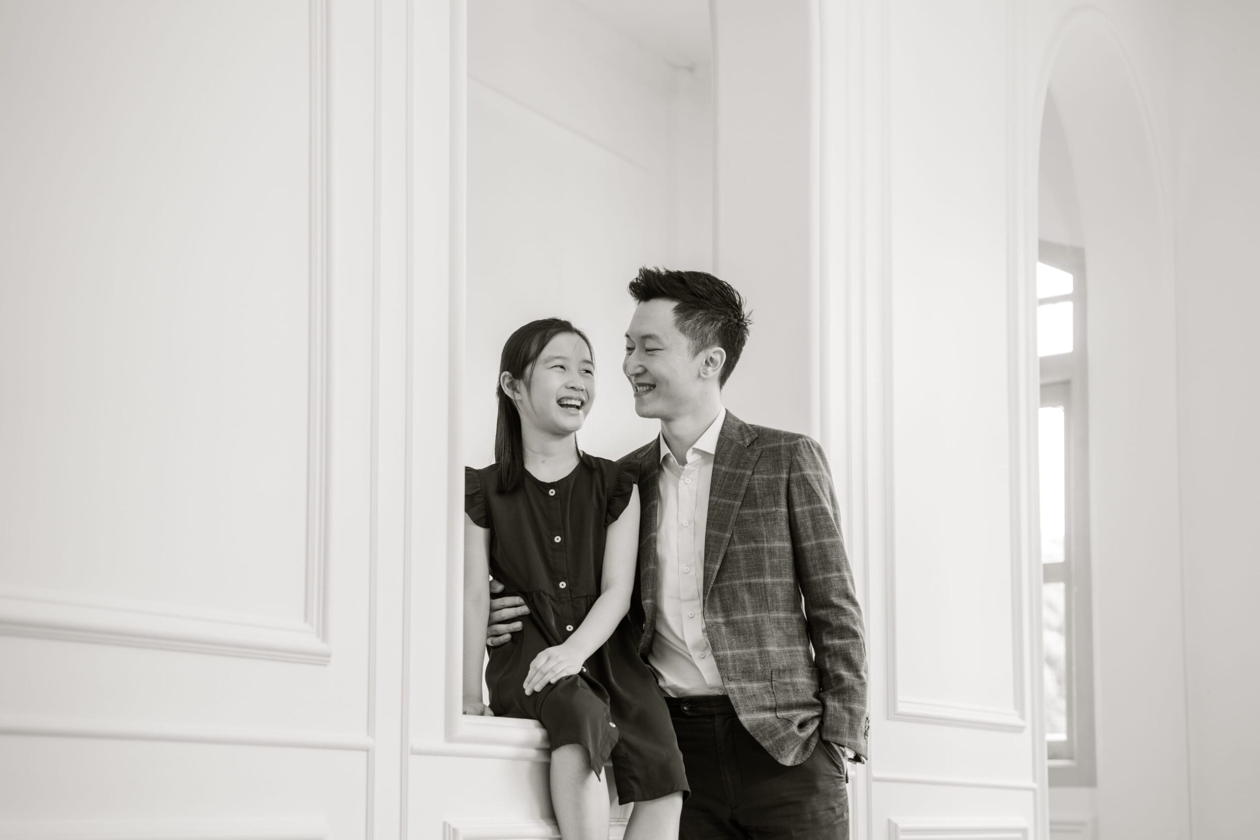 Professional Family & Multi Generation Photoshoot in Photography Studio, Singapore Father and daughter smiling at each other in a photography studio setting during a Father's Day photoshoot in Singapore, White Room Studio. Credit: White Room Studio Pte Ltd
