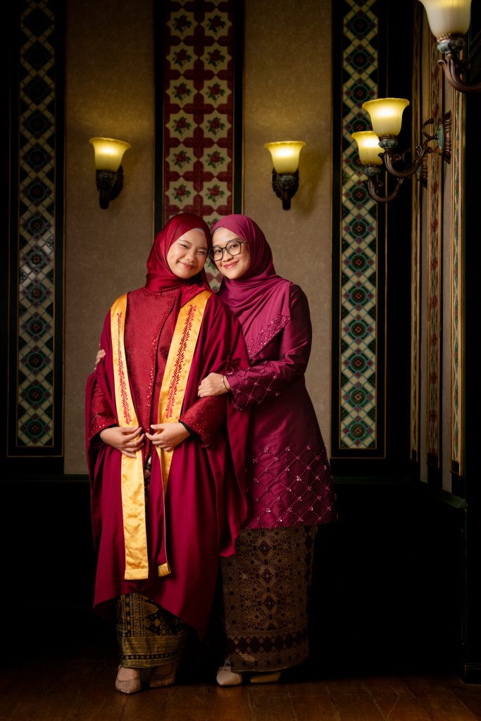 Family hugging graduate during a graduation photoshoot at heritage shophouse in Singapore