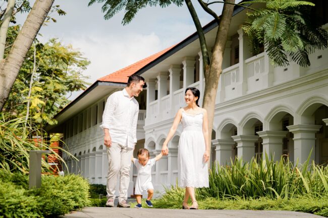 Family with mother and father holding baby son's hands during an outdoor family photoshoot in Capella Hotel Singapore. Credit: White Room Studio Pte Ltd