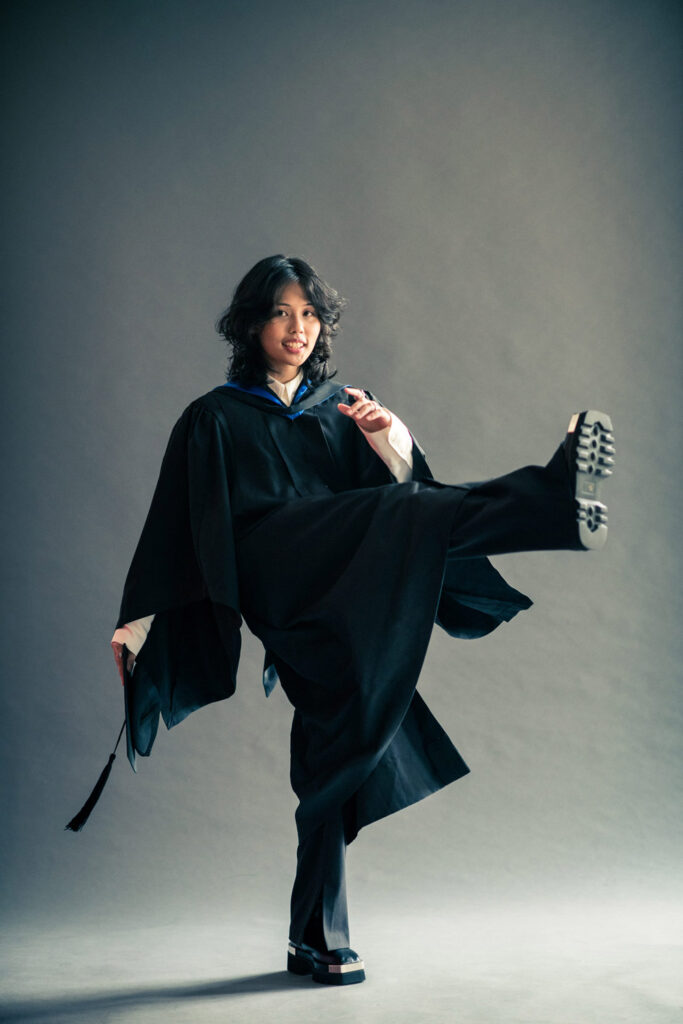 Graduate in gown and mortarboard posing for solo graduation photoshoot at White Room Studio Singapore