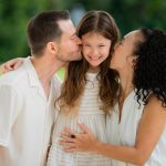 parents kissing daughter during a outdoor photoshoot photographed by White Room Studio, 219 River Valley Road, Singapore. Natural light family portrait 2026