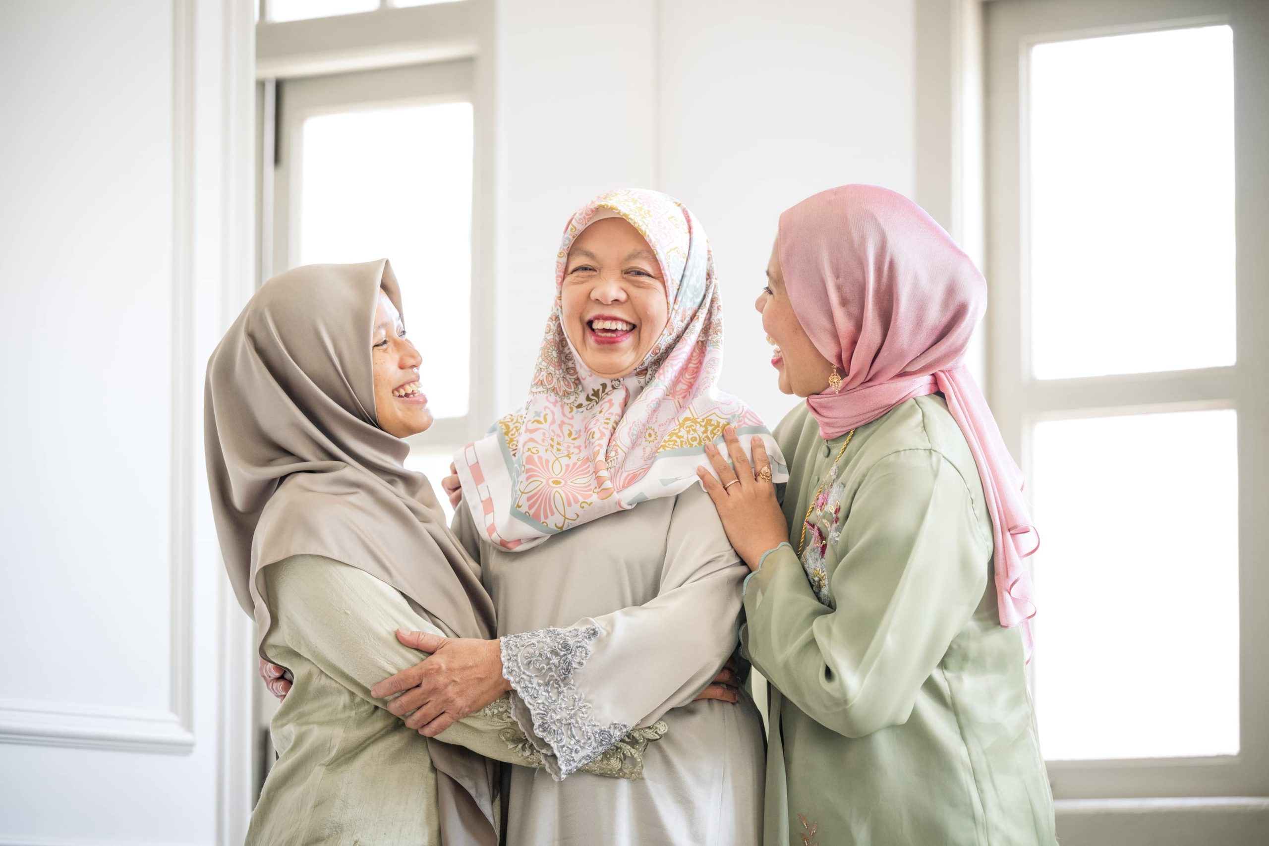 Professional Hari Raya Photoshoot in Photography Studio, Singapore Three generations of Malay women in hijab laughing warmly together during a Hari Raya family photoshoot at White Room Studio Singapore