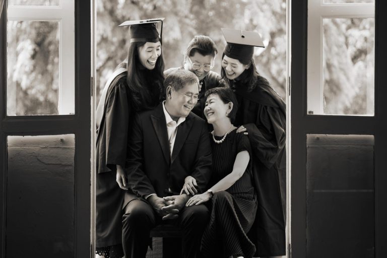 Graduates in graduation gowns and throwing their mortarboards in a photography studio setting during a family photoshoot in Singapore, White Room Studio. Credit: White Room Studio Pte Ltd