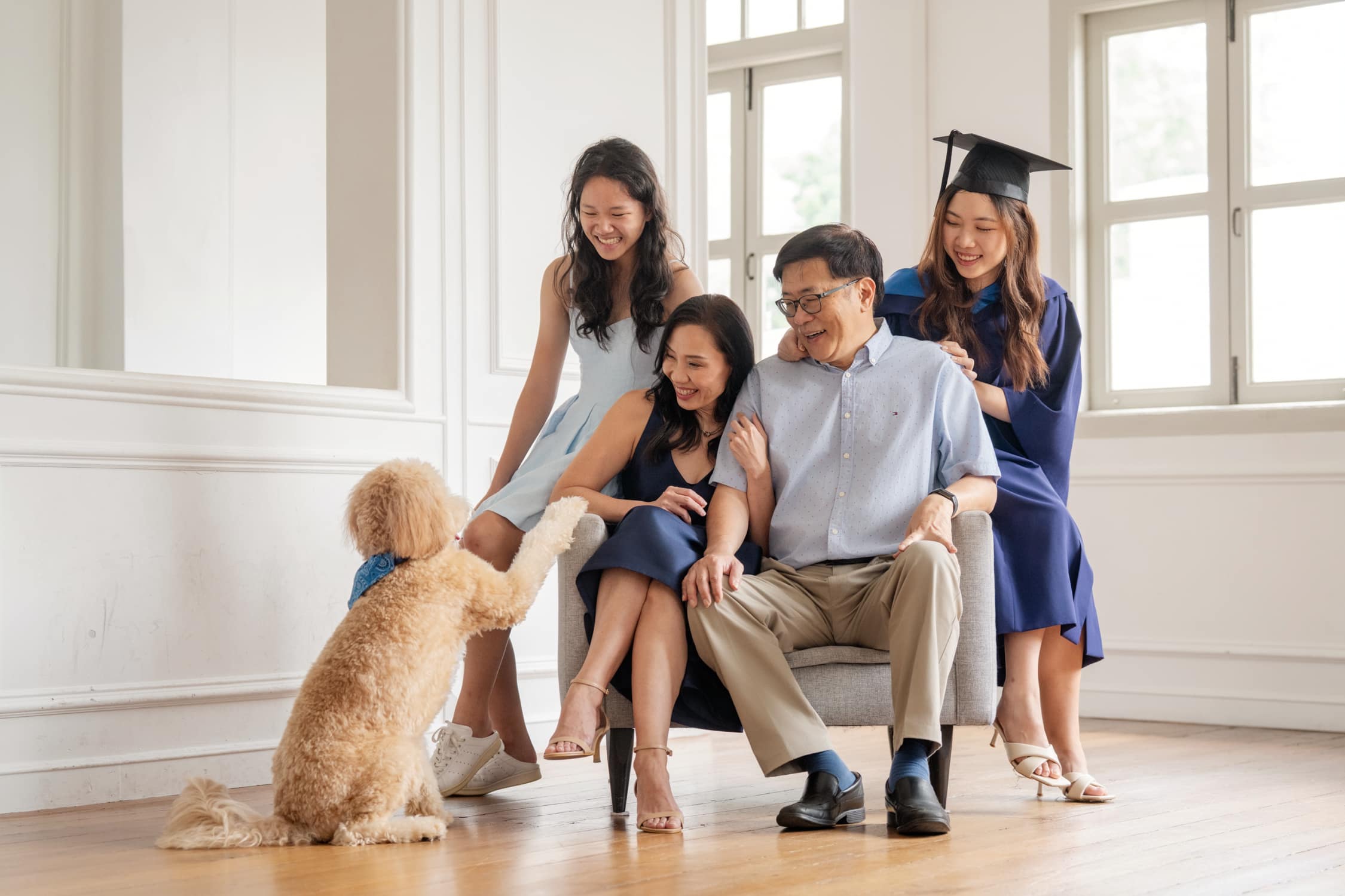 Graduation pet photoshoot of graduate in gown and cap with parents in natural light photo studio at White Room Studio, 219 River Valley Road Singapore